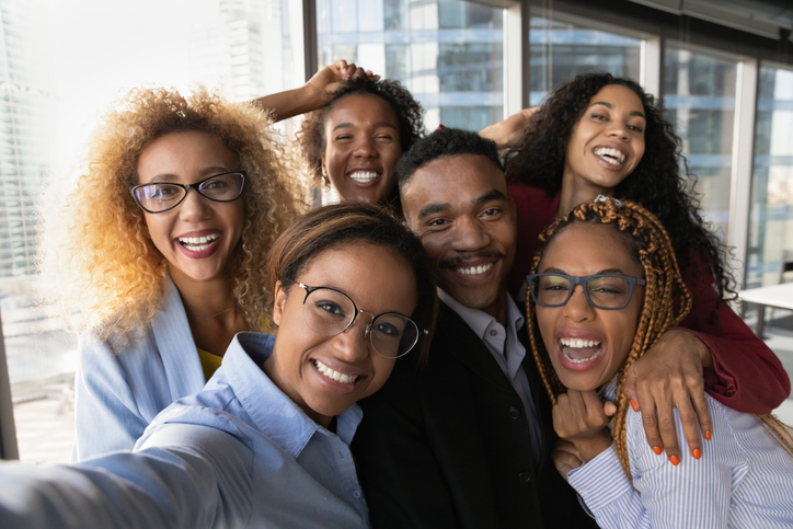 Close up portrait of overjoyed young multiracial employees team have fun posing for selfie on smartphone in office together. Happy smiling diverse multiethnic colleagues male self-portrait picture.