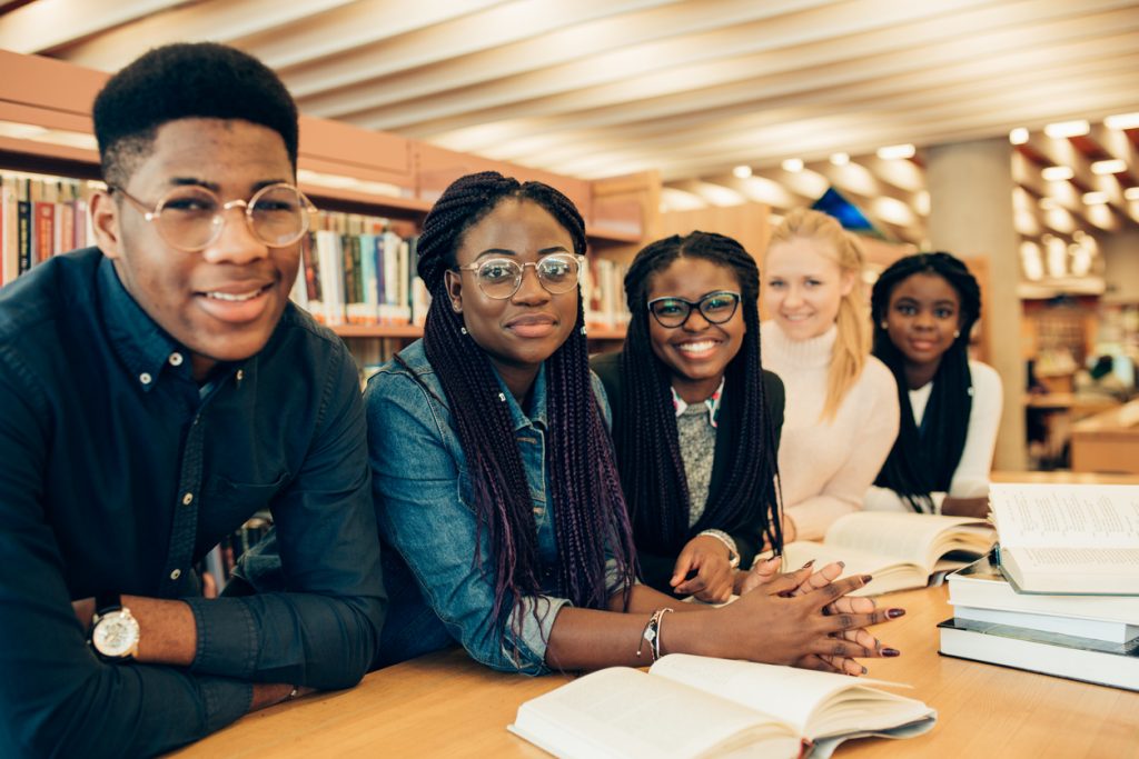 Smiling group of four black students and one white student in the library